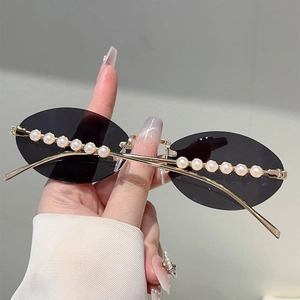 Detailed close-up of oval rimless sunglasses with gold metal frame and pearl embellishments