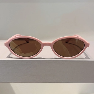 Gros plan de lunettes de soleil ovales roses avec verres bruns sur un support