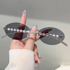 Detail of rimless oval sunglasses with silver metal frame and elegant pearl embellishments