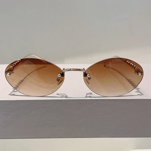 Close-up of rimless oval sunglasses with brown gradient lenses and golden pearl chain temples