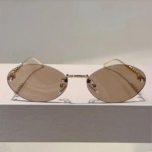 Detail of rimless oval sunglasses with brown lenses and golden textured temples