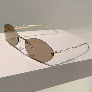 Detailed shot of golden metal temple with elegant pearls on oval rimless sunglasses
