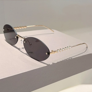 Detail of oval rimless sunglasses with gold metal temples and elegant pearl embellishments