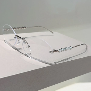 Detailed view of oval rimless glasses with silver metal temples and pearl embellishments