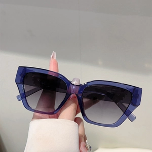 Detailed close-up of oversized blue translucent sunglasses with gradient grey lenses