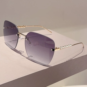 Détail de lunettes de soleil sans monture à verres violets dégradés avec des branches perlées