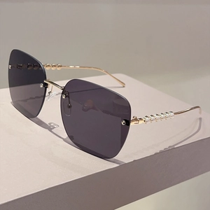 Détail de lunettes de soleil carrées sans monture avec branches dorées et perles