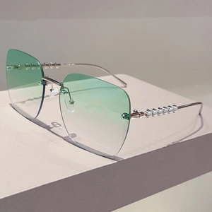 Détail de lunettes de soleil carrées sans monture avec branches ornées de perles et verres dégradés