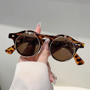 Detail of tortoise shell round flip-up sunglasses with golden metal rim and retro design