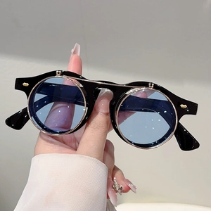 Detail of round flip-up sunglasses with black frames, blue lenses and gold metal accents