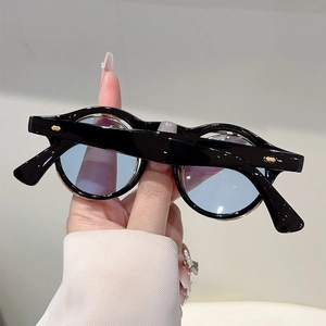Detail of round black frame sunglasses with light blue lenses and gold rivet accents