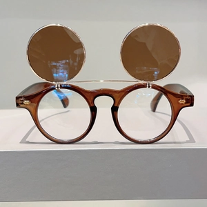 Detail of round flip-up sunglasses with amber lenses and stylish gold metal hinges