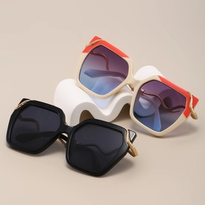 Detail of oversized sunglasses with metallic snakeskin chain temples on white podium
