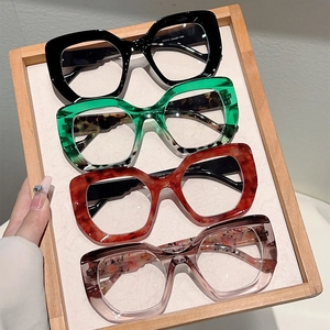 Detail view of stylish leopard print and colorful cat-eye frames on a wooden tray