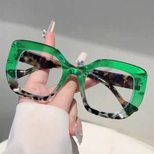 Macro detail of cat-eye glasses with green upper frame and leopard print lower part
