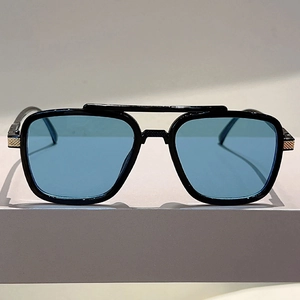 Detail of double-bridge oversized sunglasses with gold metal hinges and blue lenses