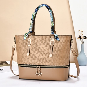 Detail of tan faux leather tote bag with V-shaped weave and silk scarf wrapped handle