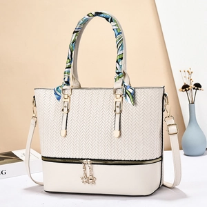 Detail of off-white tote bag with woven texture and scarf-wrapped handles
