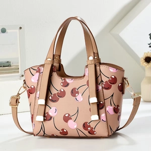 Detail view of pink dumpling bag with cherry print, gold D-ring and adjustable strap