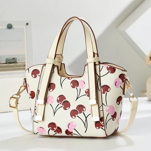 Detailed macro of cherry print handbag with golden hardware and adjustable strap