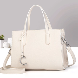 Détail du sac à main beige texture litchi avec pendentif C argenté et bandoulière