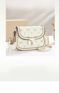 Detail of lychee leather saddle bag with animal prints and plush sheep charm