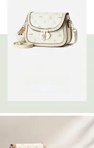 Detail of cream white saddle bag featuring LNBOE prints and a fuzzy pompom charm