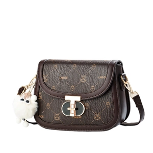 Brown leather saddle bag with LNBOE pattern and plush charm shown from 45-degree angle