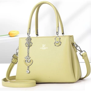 Detail of lime green tote bag featuring silver heart pendant and metal brand logo