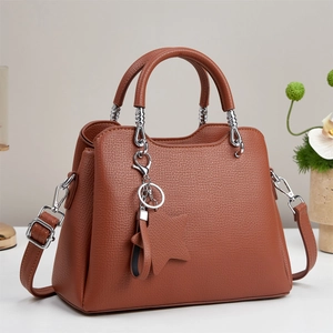 Brown litchi grain trapezoid handbag with twin handles and star charm on grey background