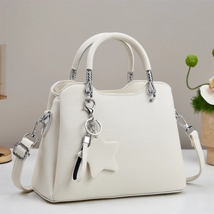 Close-up of white lychee leather texture and silver star charm on the tote bag