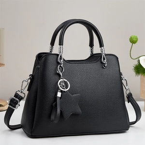 Detail of black lychee grain leather tote bag with star pendant and silver hardware