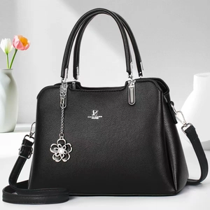 Close-up of pebble leather texture with silver logo and floral charm on black handbag