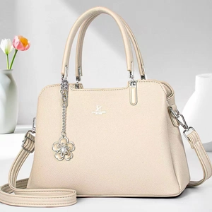 Close-up of beige lychee leather handbag with silver hardware and flower charm