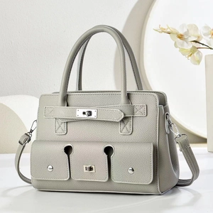 Detailed view of grey pebble leather handbag with silver twist lock and twin front pockets