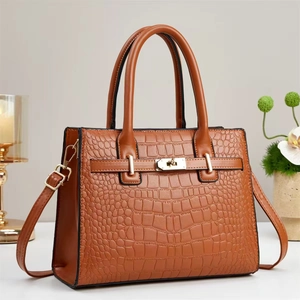 Detailed view of brown crocodile texture handbag featuring golden turn-lock closure
