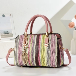 Colorful striped woven handbag with pink leather straps and a gold pearl leaf charm
