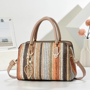 Detail of bohemian striped woven handbag with leather handles and gold leaf pendant