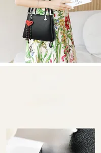 Close-up of black litchi leather handbag with heart pendant and woven tassel detail