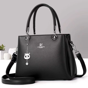 Close-up of black lychee leather handbag with metal logo and cute panda pendant