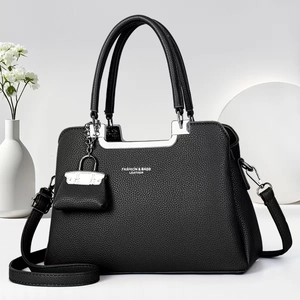 Detail of black lychee grain leather handbag with silver metallic handle and mini pendant