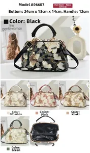 Detail of floral embroidery, leaf charm and metal clasp on vintage top-handle bag