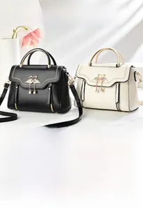 Detail of elegant leather handbag with golden swan clasp and pearl tassel accessory