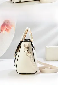 Side view of cream leather trapezoid handbag with gold hardware and removable strap