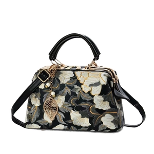 Retro black handbag featuring floral embroidery, pearl pendant, and gold metal clasp