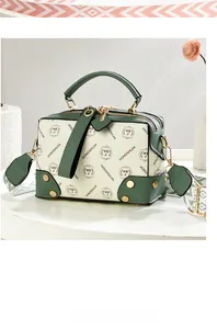 Detail of green and white patterned Boston bag with woven shoulder strap and metal rivets