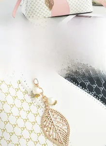Detail of pink and white tote bag with golden leaf pendant and pearl decoration