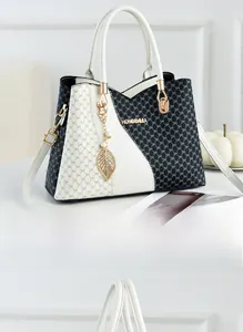 Detail of black and white printed handbag with golden hardware and leaf charm