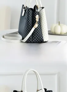 Side view of black and white tote bag with DH letter pattern and gold hardware
