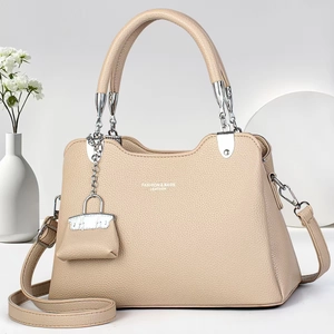 Détails d'un sac à main beige en cuir grainé avec finitions argentées et charm miniature